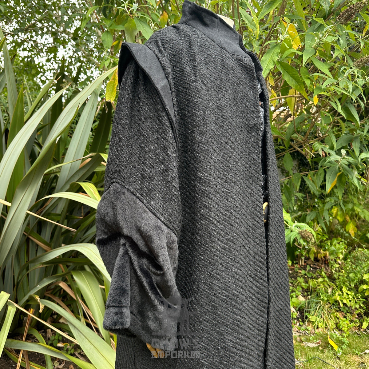 Black medieval LARP robe with textured fabric and padded sleeves, side view.