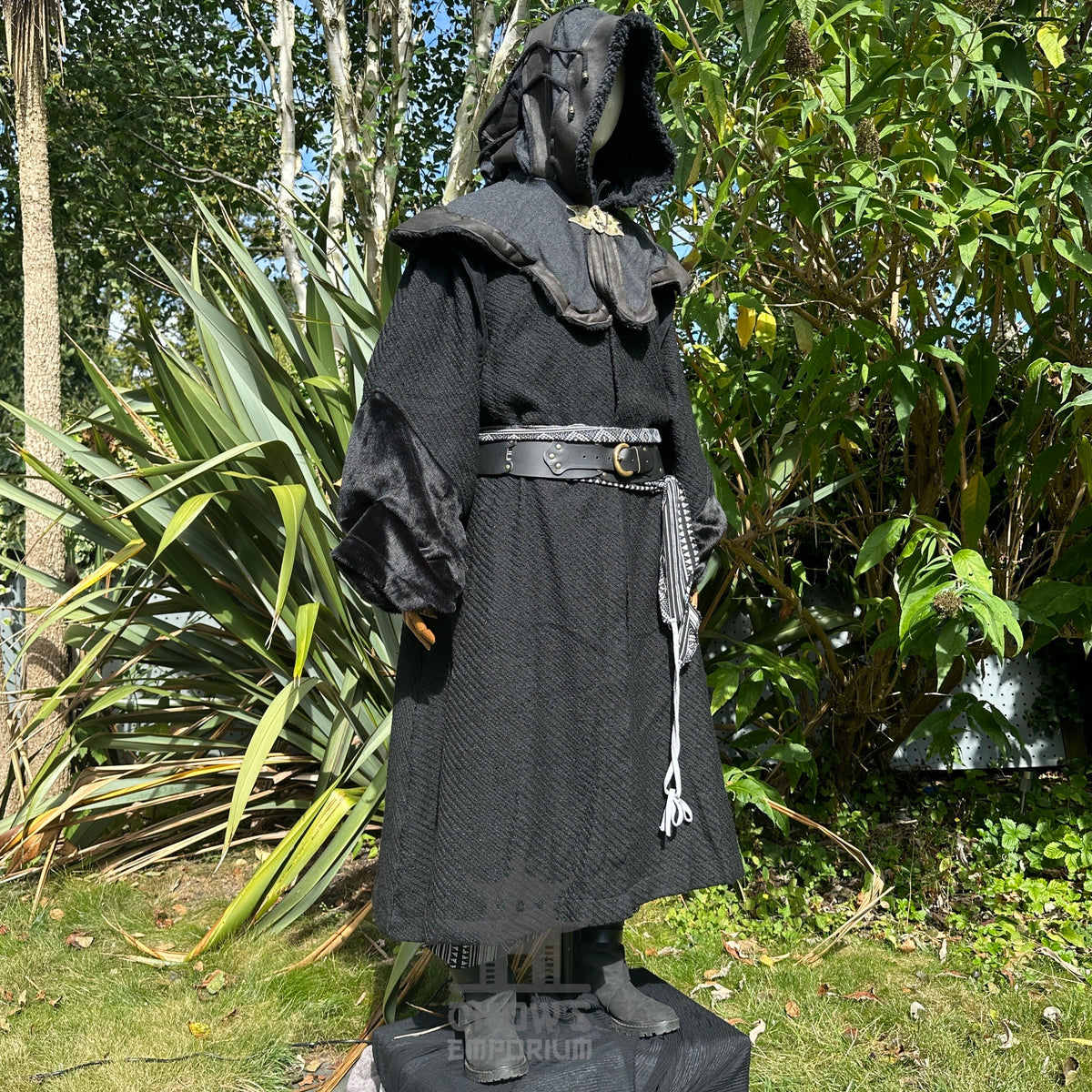 Medieval LARP costume side view, featuring a black robe, hood, arm wraps, belt and sash.