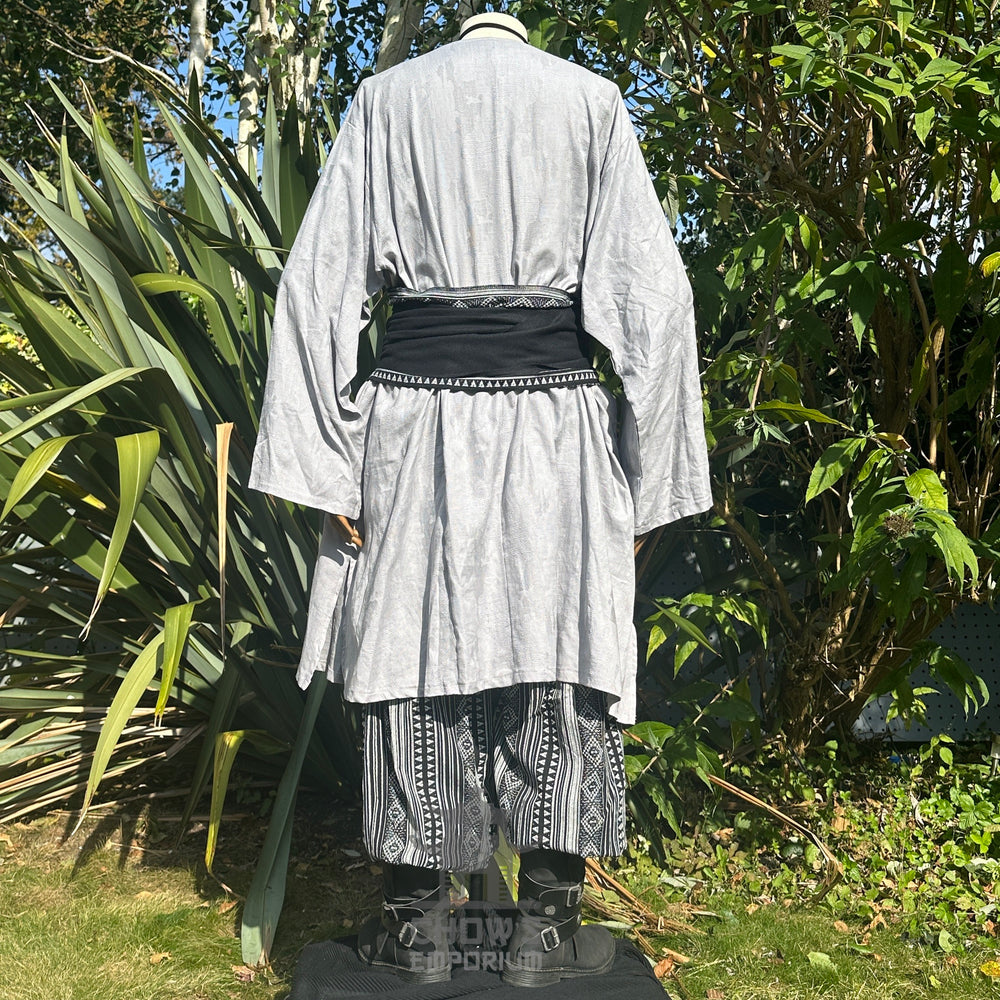 Medieval LARP outfit back view, featuring a grey tunic, black & white trousers and matching sash. For Renaissance Faire and historical roleplay events.
