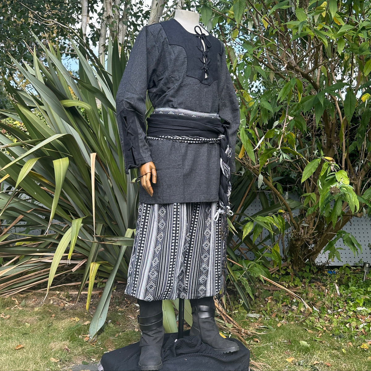 Medieval LARP outfit side view, featuring a grey two-tone shirt, black trousers and sash.