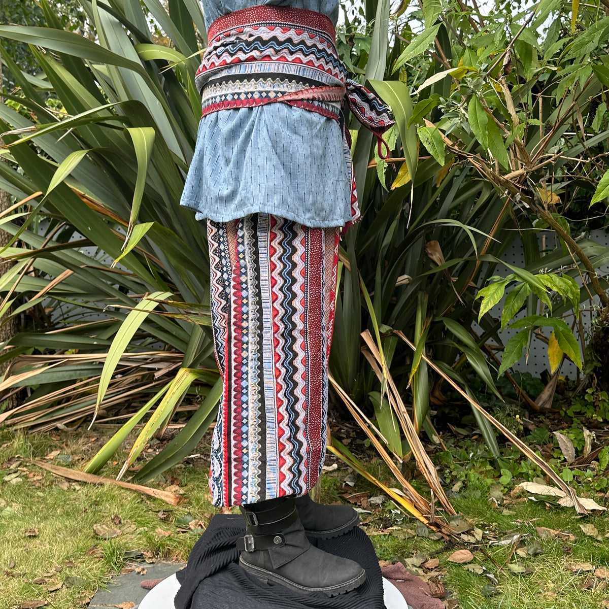 Blue shirt, zigzag pants, and sash, side view of LARP Nordic outfit.