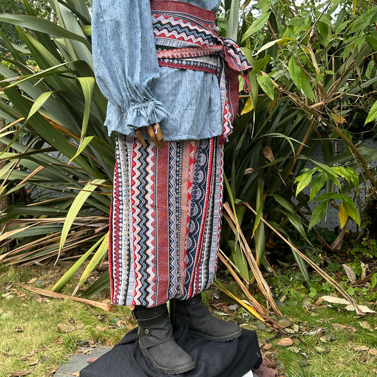 Blue and red Nordic LARP outfit with zigzag shirt, pants, and sash.