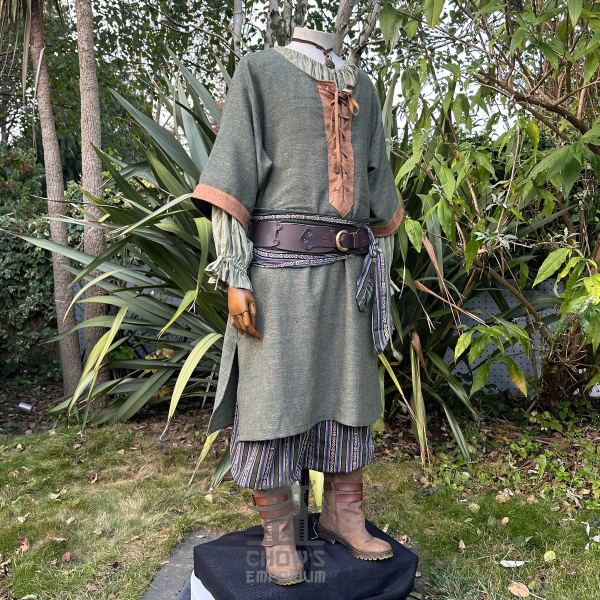 Mannequin in a medieval LARP outfit with green tunic, striped pants, sash, belt.