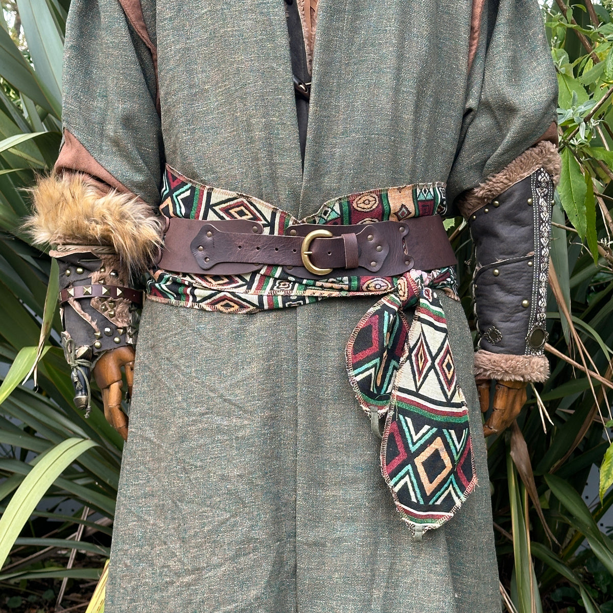 Green medieval LARP robe with geometric sash, leather belt, fur vambraces.
