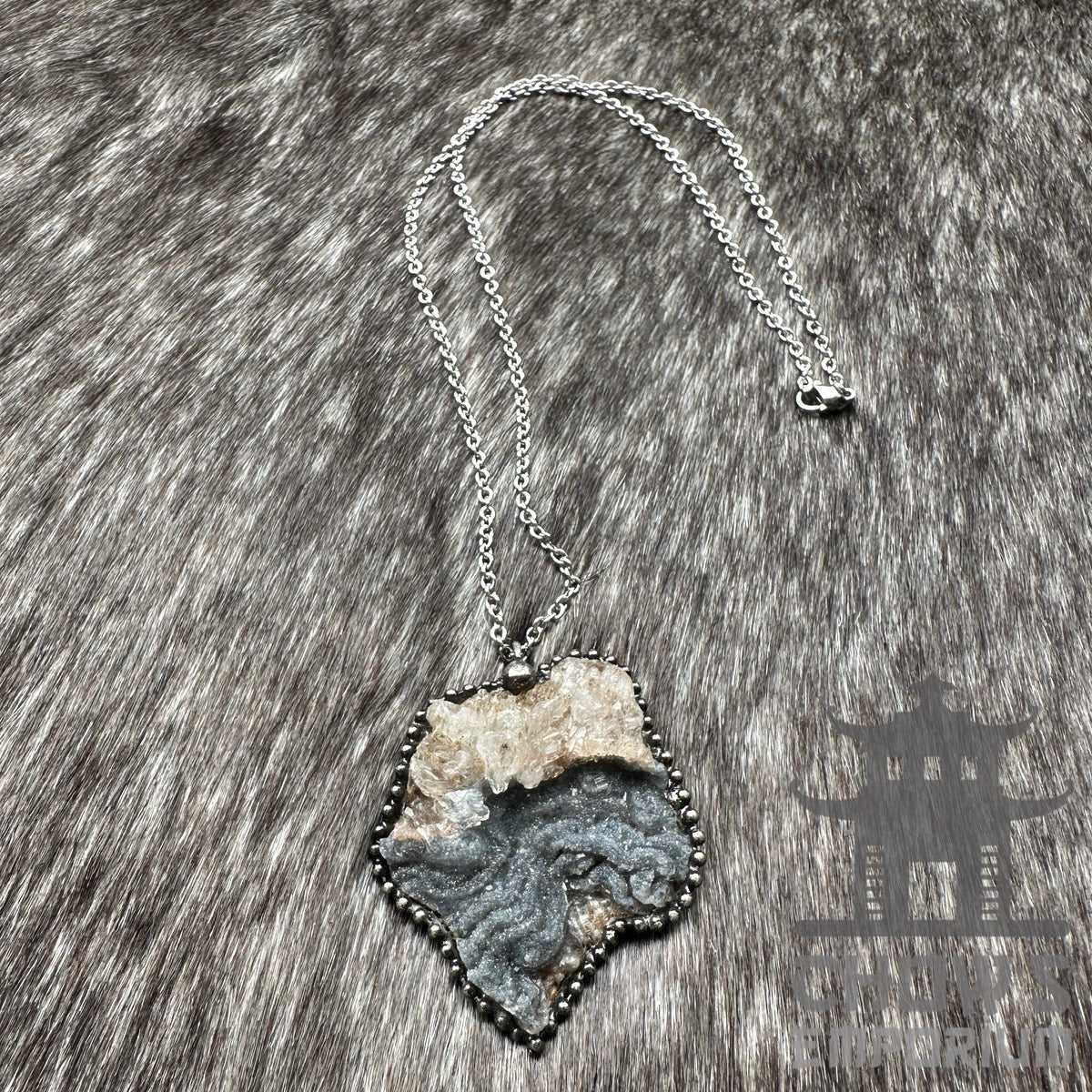 Silver chain with rough stone pendant on textured fur, medieval accessory.