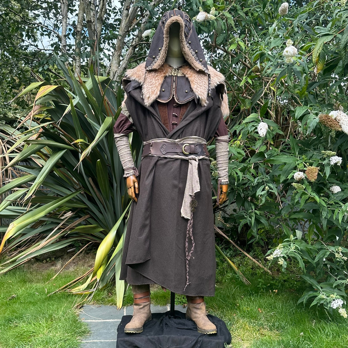 Forest Ranger LARP attire, brown cloak and hood, arm wraps background.