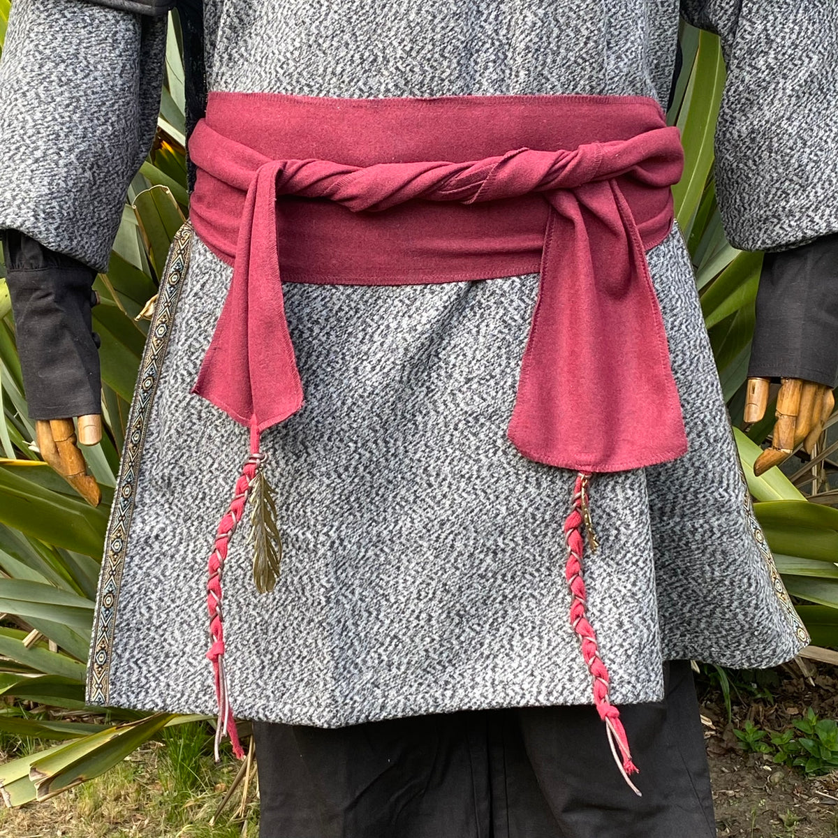 Medieval LARP waist sash with braided tassels on a grey herringbone tunic.