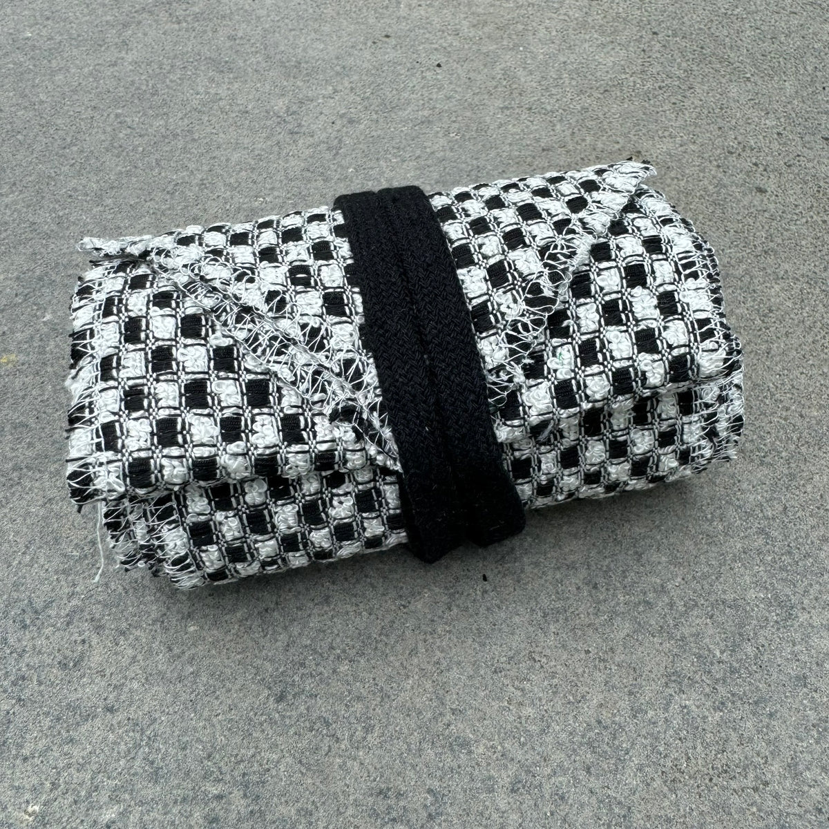 Checkered black and white LARP sash, folded, textured fabric, top view.