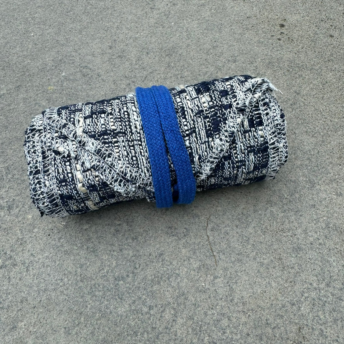 Blue and white knitted sash for LARP, rolled, with textured pattern.