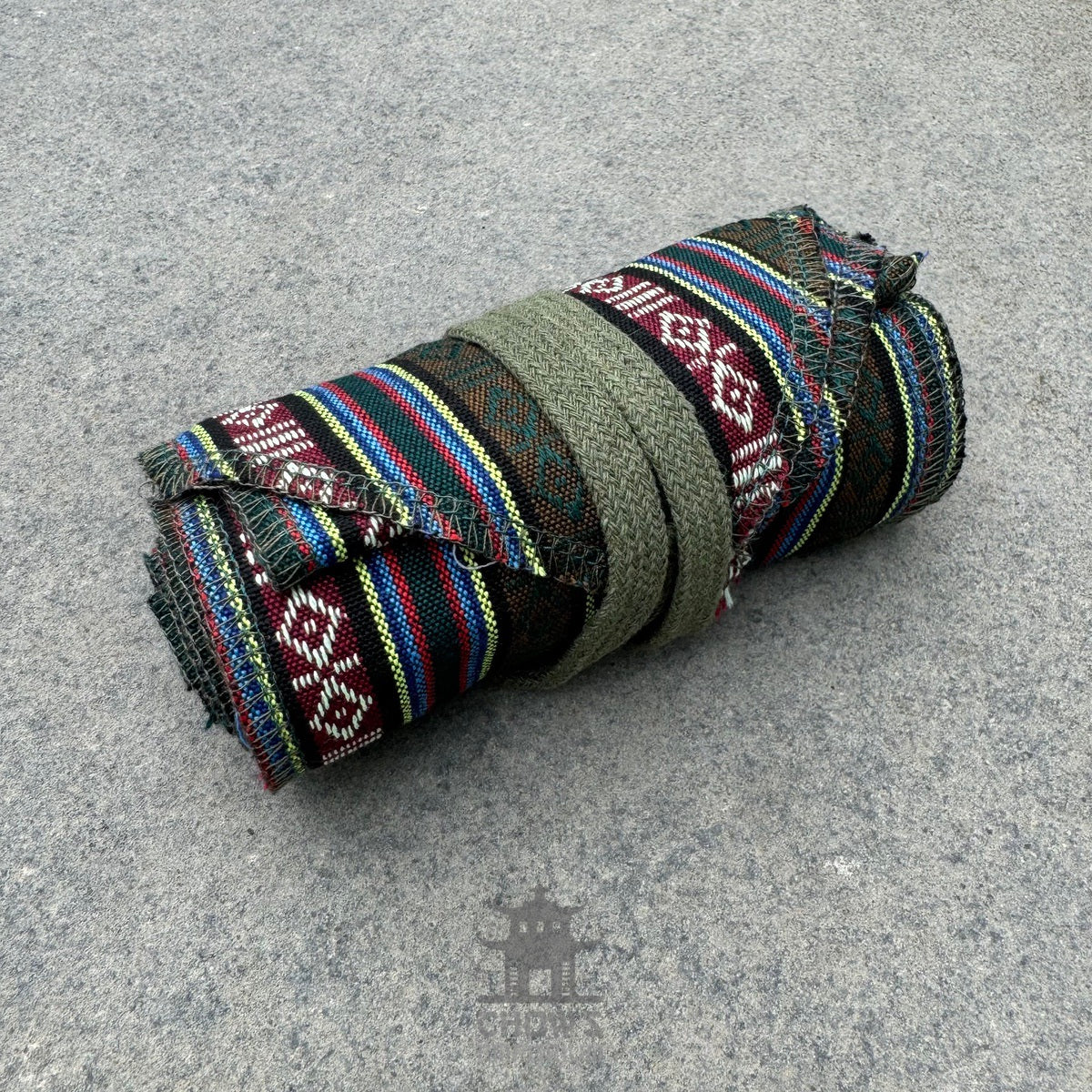 LARP outfit rolled, green and multi-striped fabric, woven texture, side view.