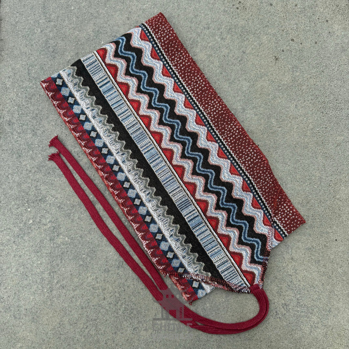 Red and blue zigzag medieval LARP sash on a grey surface.