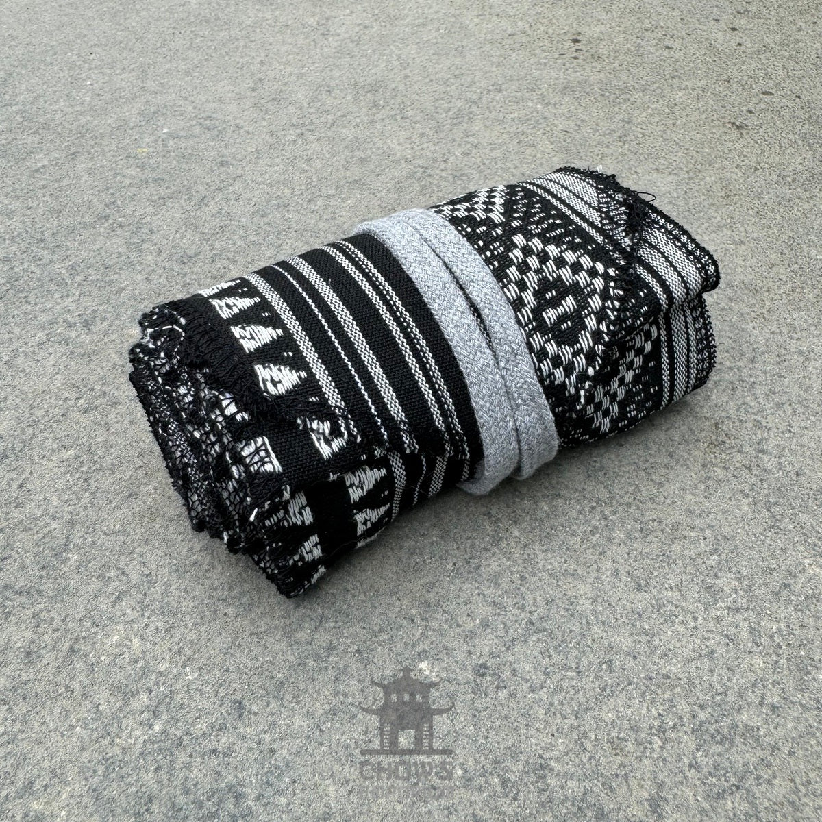 Black and grey medieval LARP sash, folded, woven pattern, close-up view.