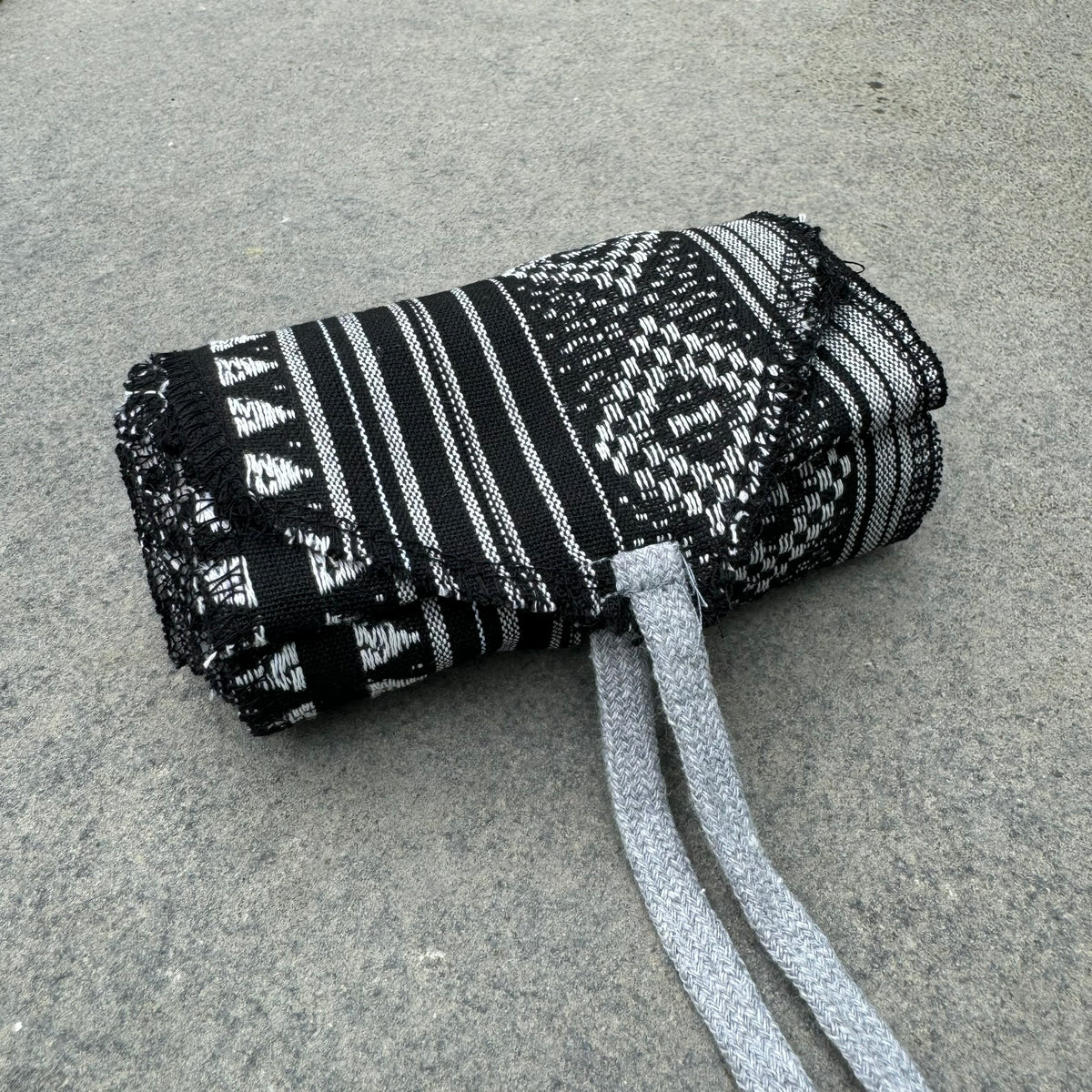 Black and white patterned LARP belt and sash set on concrete surface.