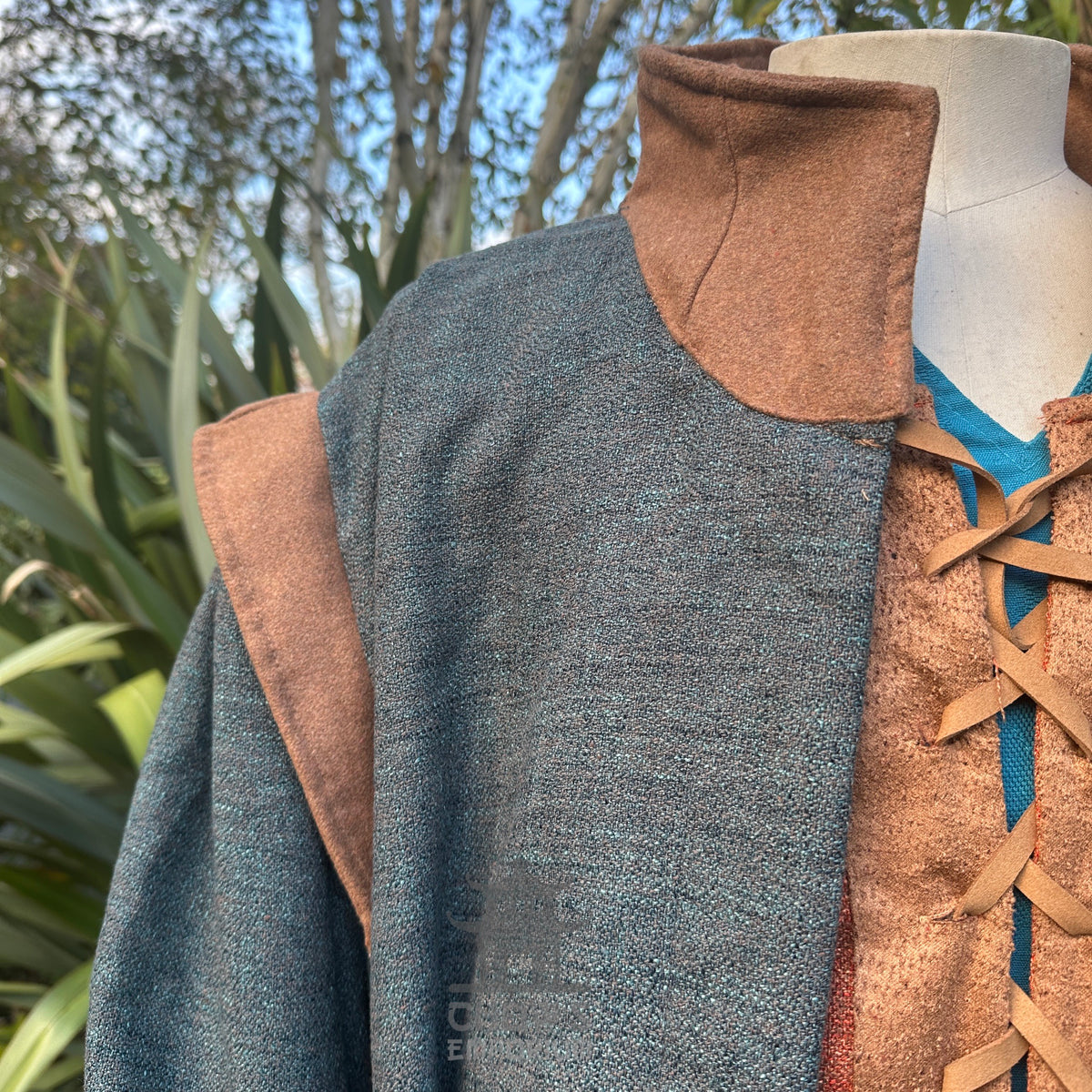 Bust view of teal medieval LARP robe with brown cross-lace detail.