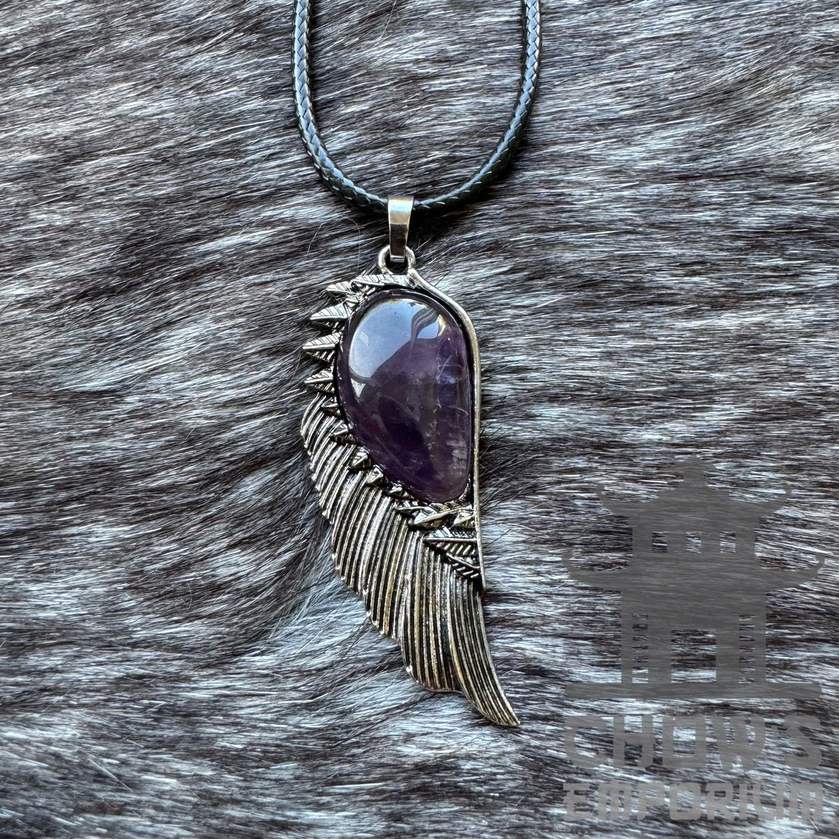 Amethyst and feather necklace, medieval style, on a textured surface.