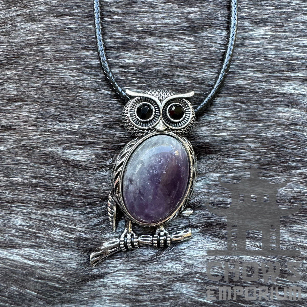 Silver owl necklace with dark amethyst set against fur, for medieval LARP.