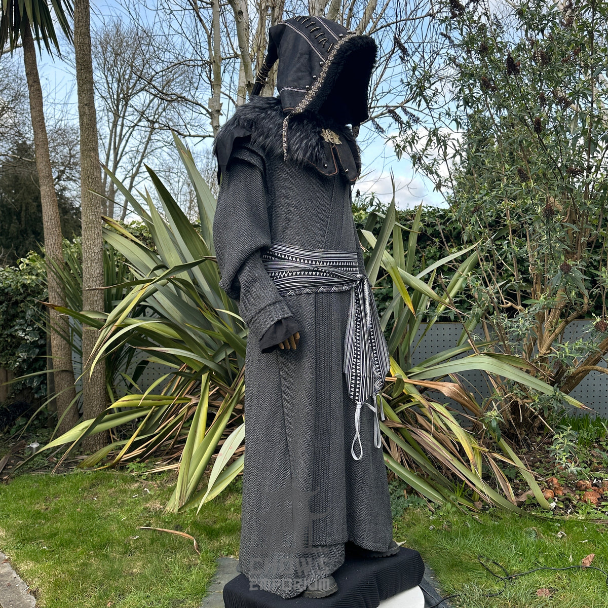 Medieval LARP costume side view, featuring a grey full length robe, black faux leather hood.