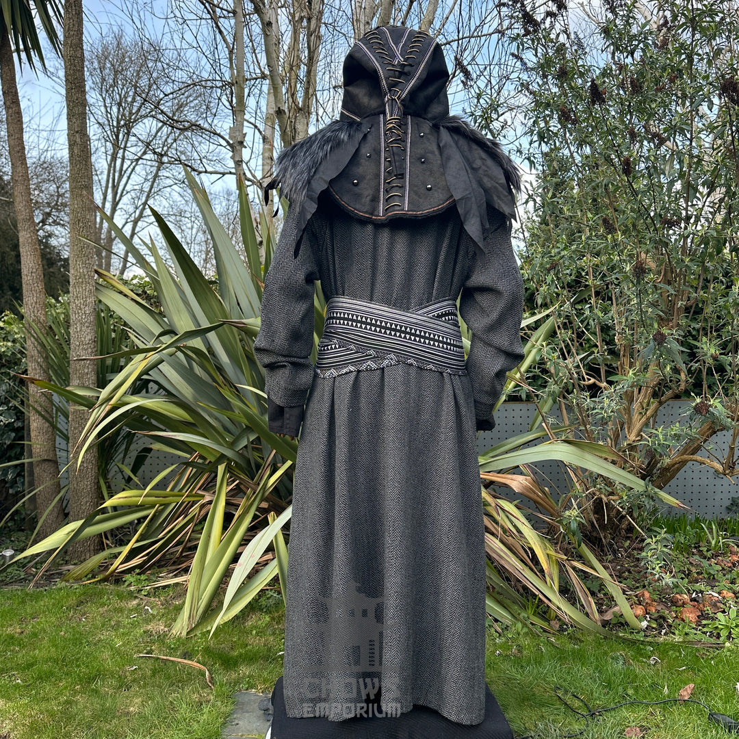 Back view of grey herringbone robe in a LARP medieval garden scene.