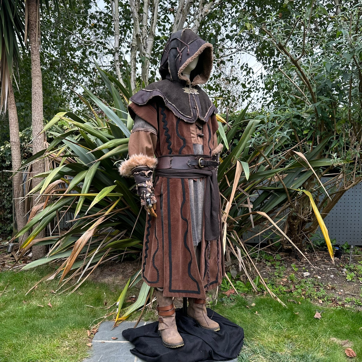 Brown-green medieval LARP hood with intricate trim, side view.