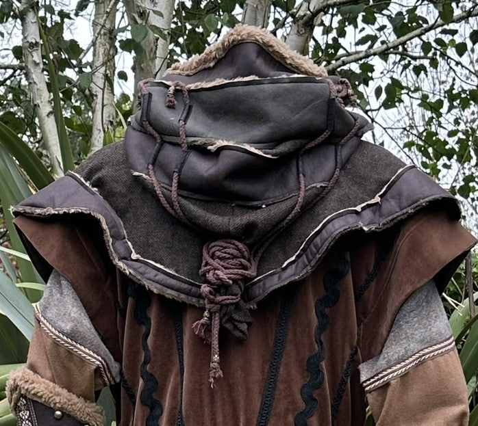 Rear view of brown and green hooded LARP cloak with detailed faux leather layers.