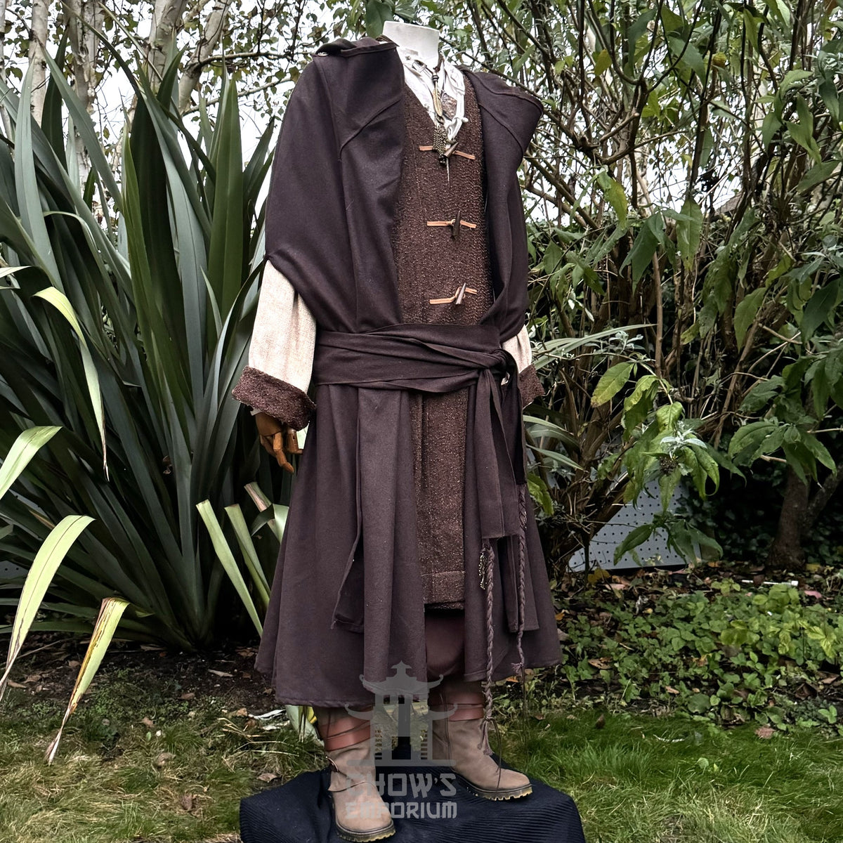 Medieval LARP costume side view featuring hooded cloak, pirate coat, trousers, sash and necklace.