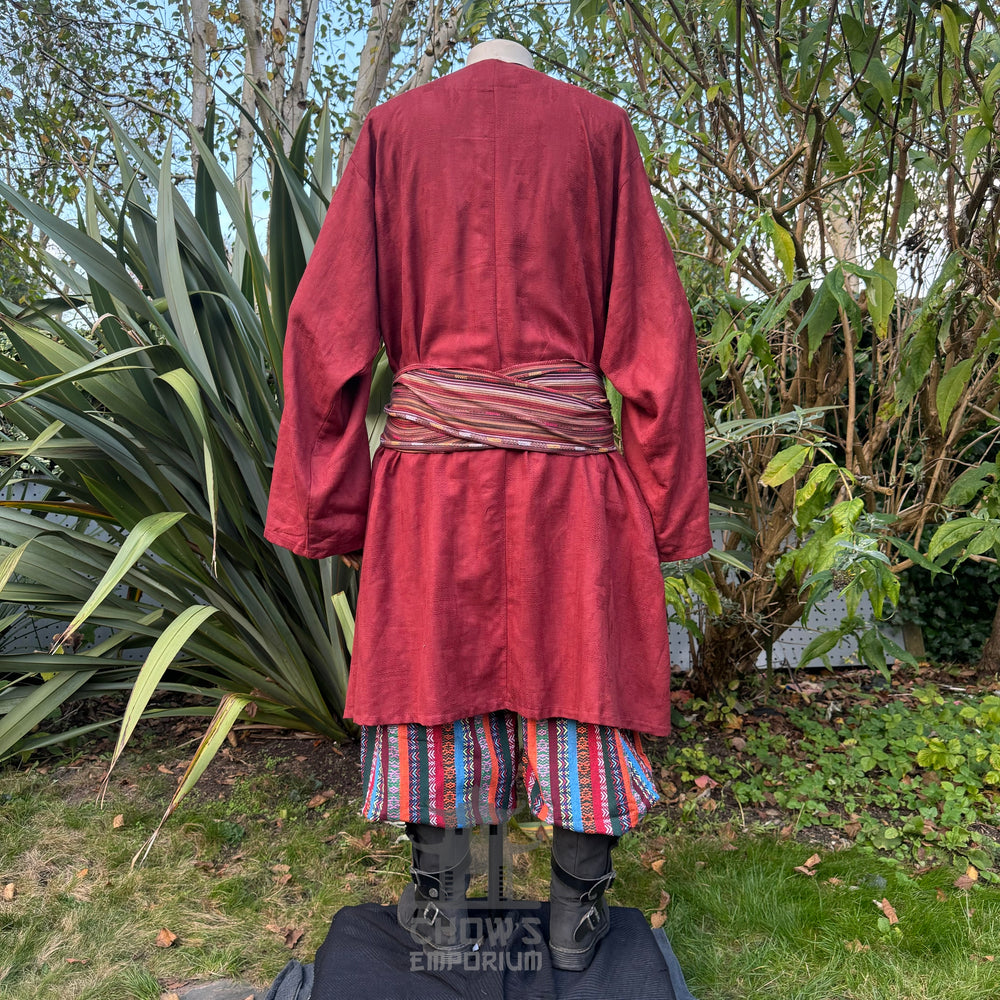 Medieval LARP outfit back view, featuring a red tunic, multi-striped trousers and sash. For Renaissance Faire and historical roleplay events.