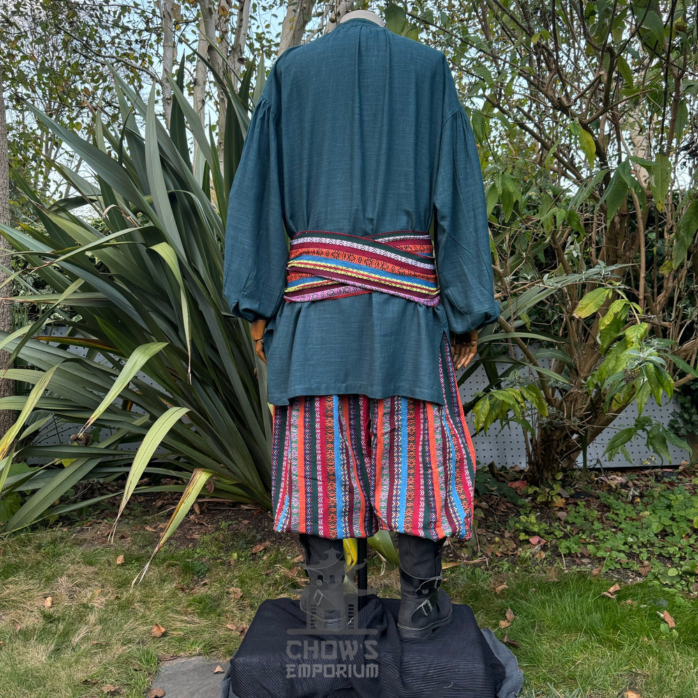 Medieval LARP outfit back view, featuring a teal shirt, multi-striped trousers and matching sash. For Renaissance Faire and historical roleplay events.