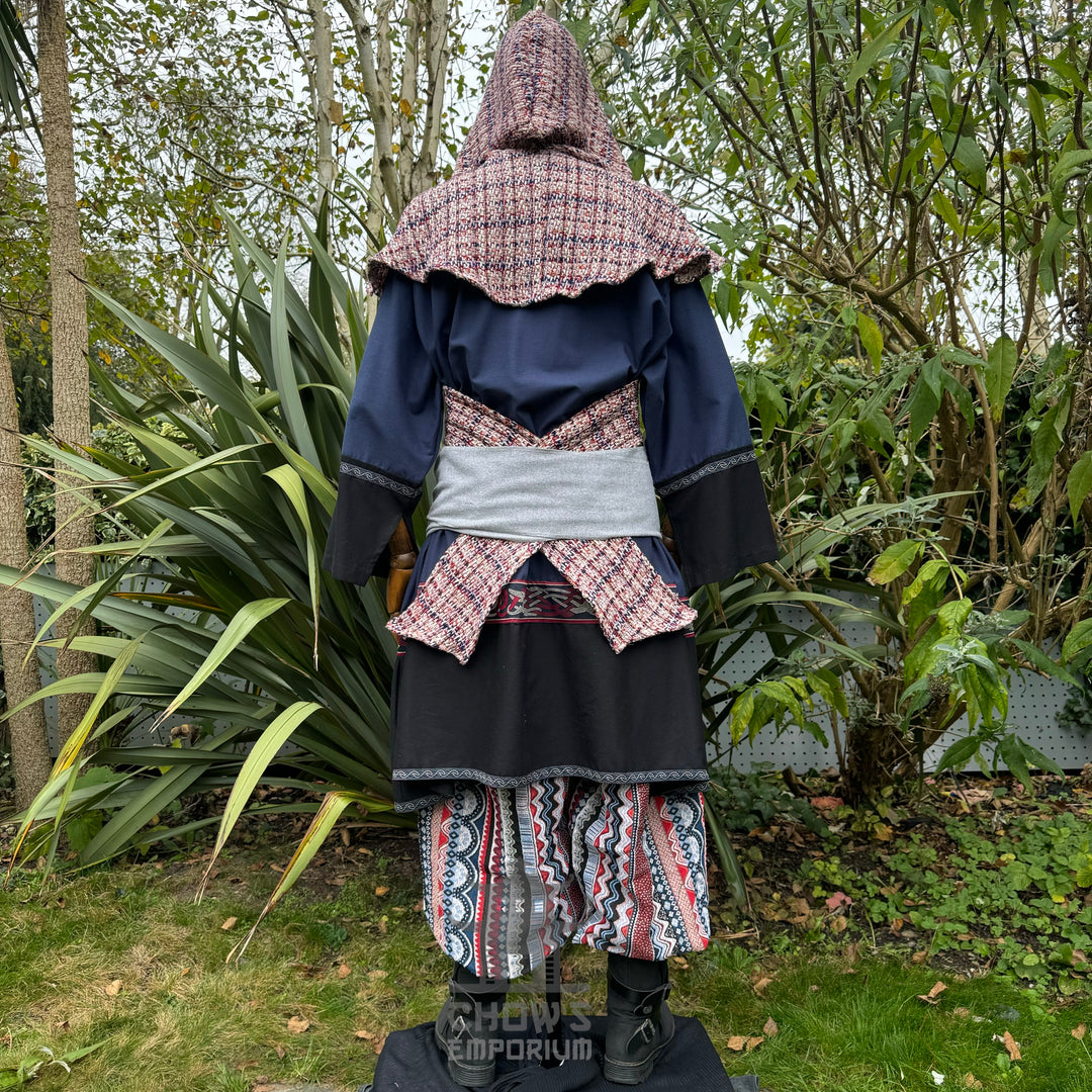 Medieval LARP outfit back view, featuring a blue and black tunic, patterned trousers, and sash. For Renaissance Faire and historical roleplay events.