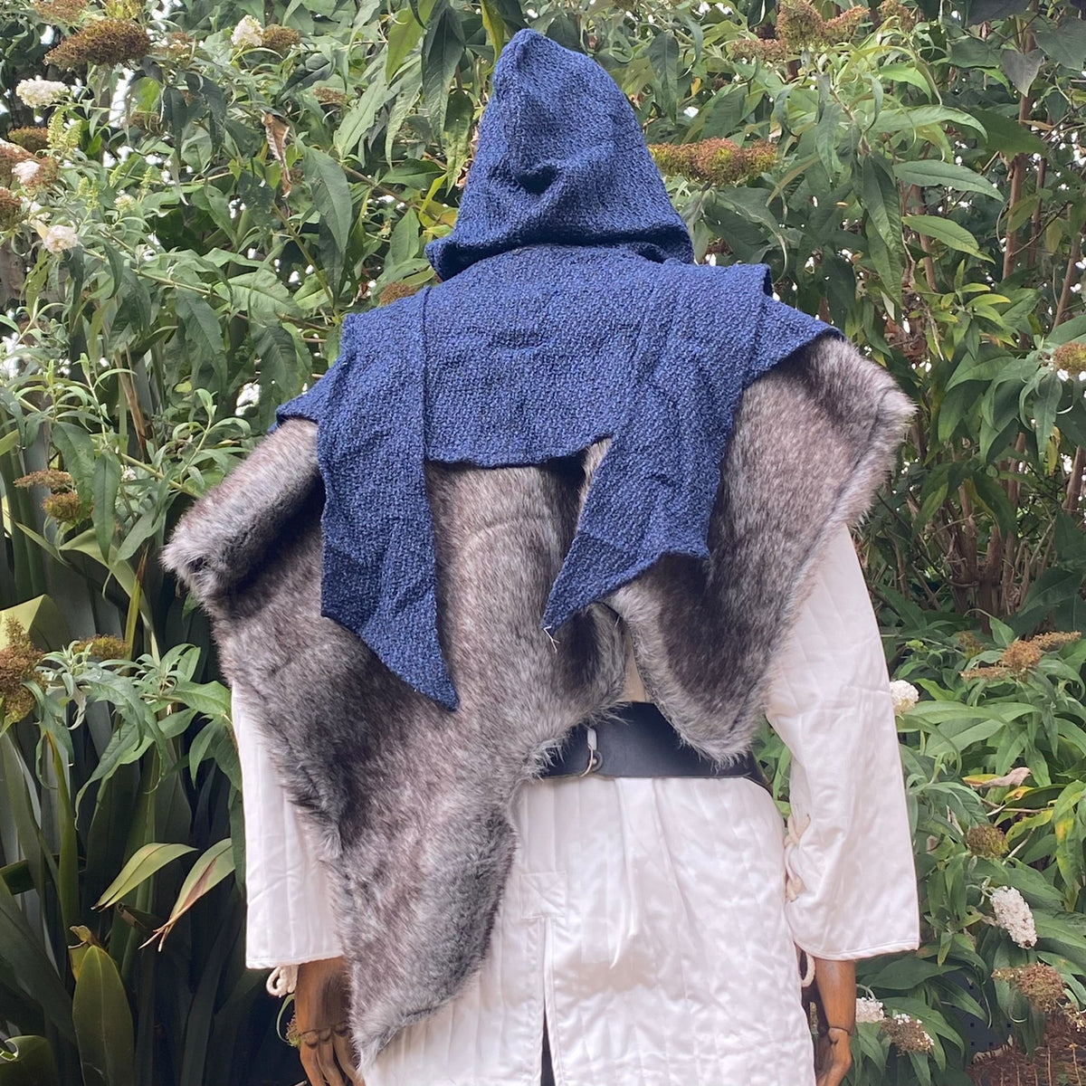 Medieval LARP outfit back view, featuring a blue wrap-around hood, and grey faux-fur mantle.