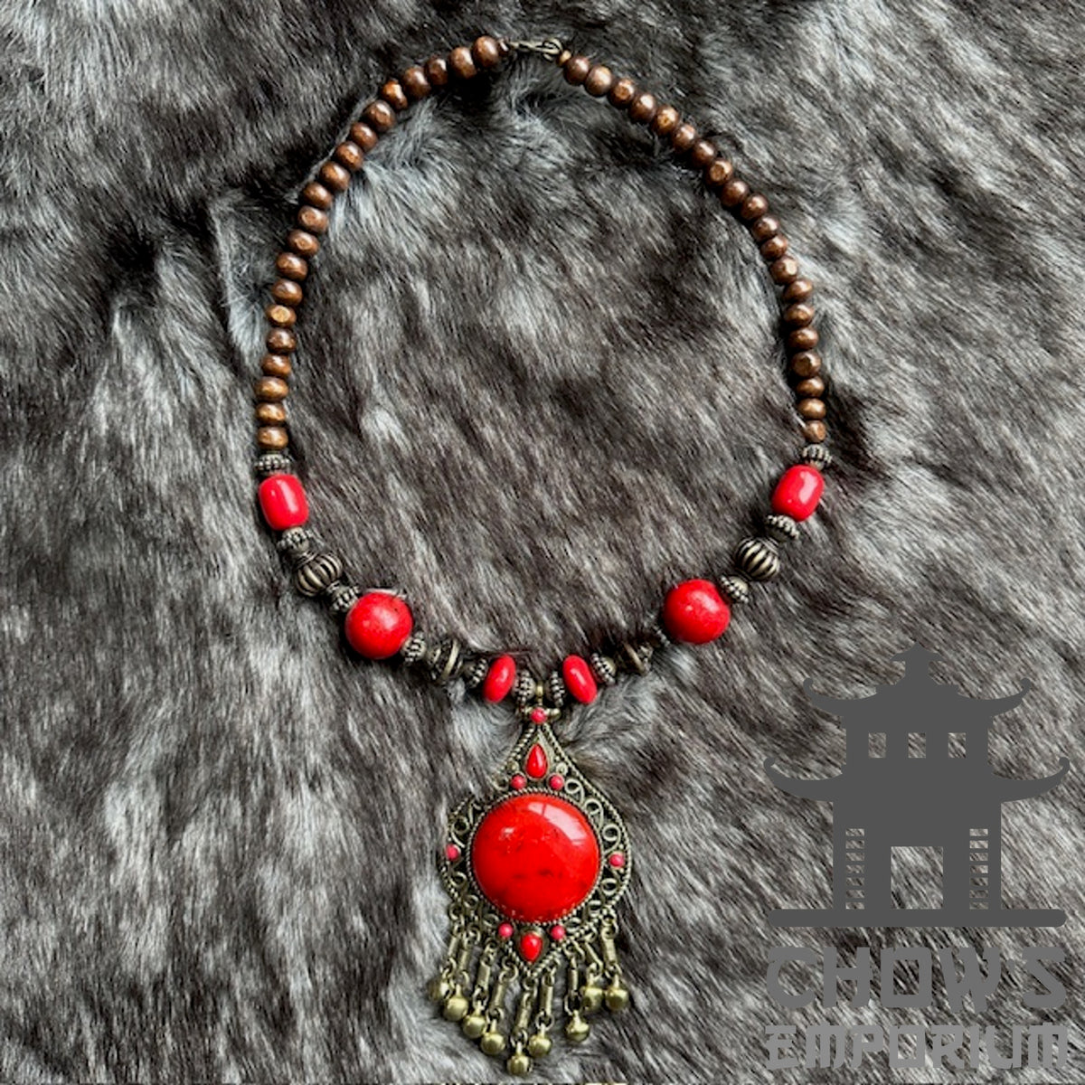 Red bohemian LARP necklace with wooden and ornate beads on fur background.