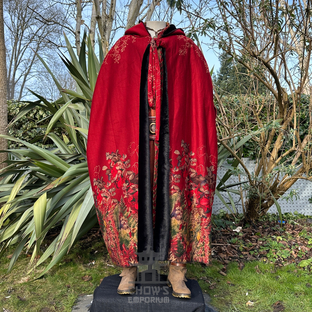 Crimson cloak on mannequin, floral embroidery, medieval LARP setting.