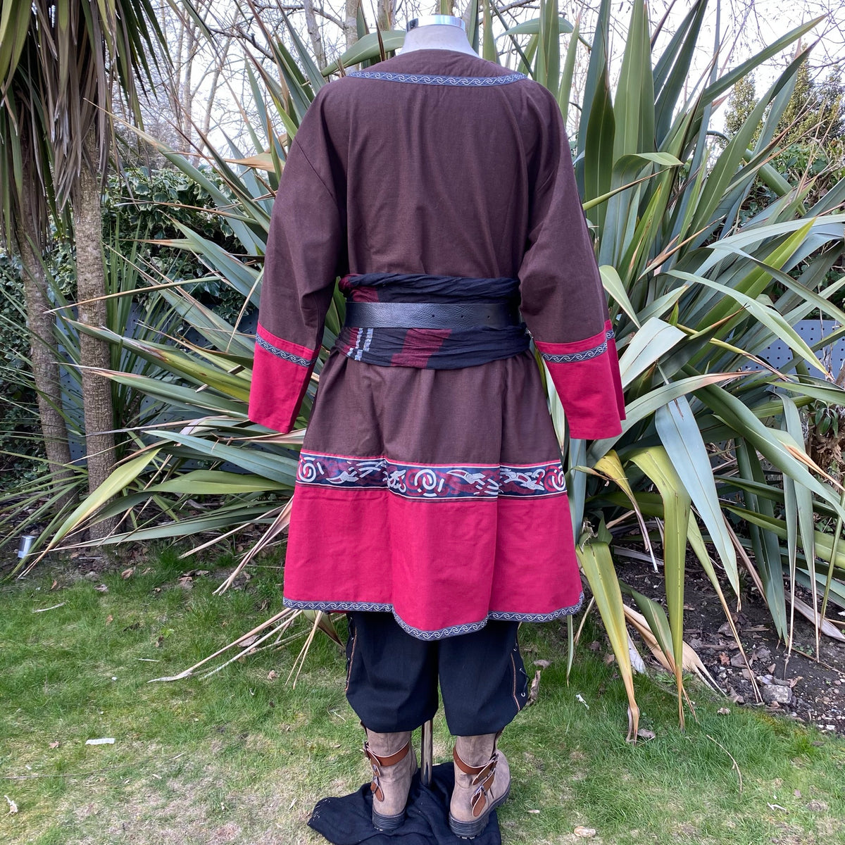 Back view of brown-red LARP tunic with black belt and decorated hem.