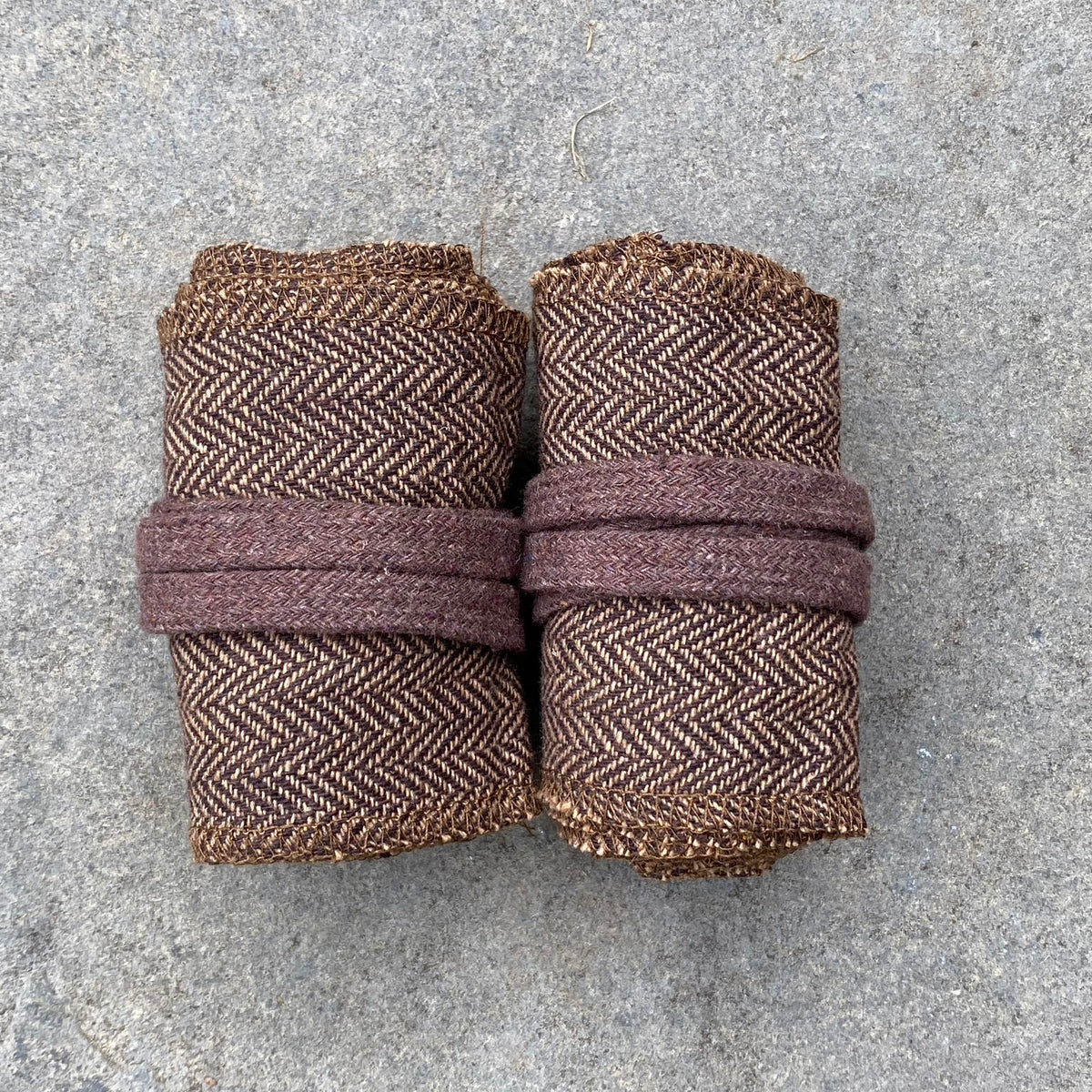 Brown herringbone medieval wraps rolled up on stone surface for LARP.