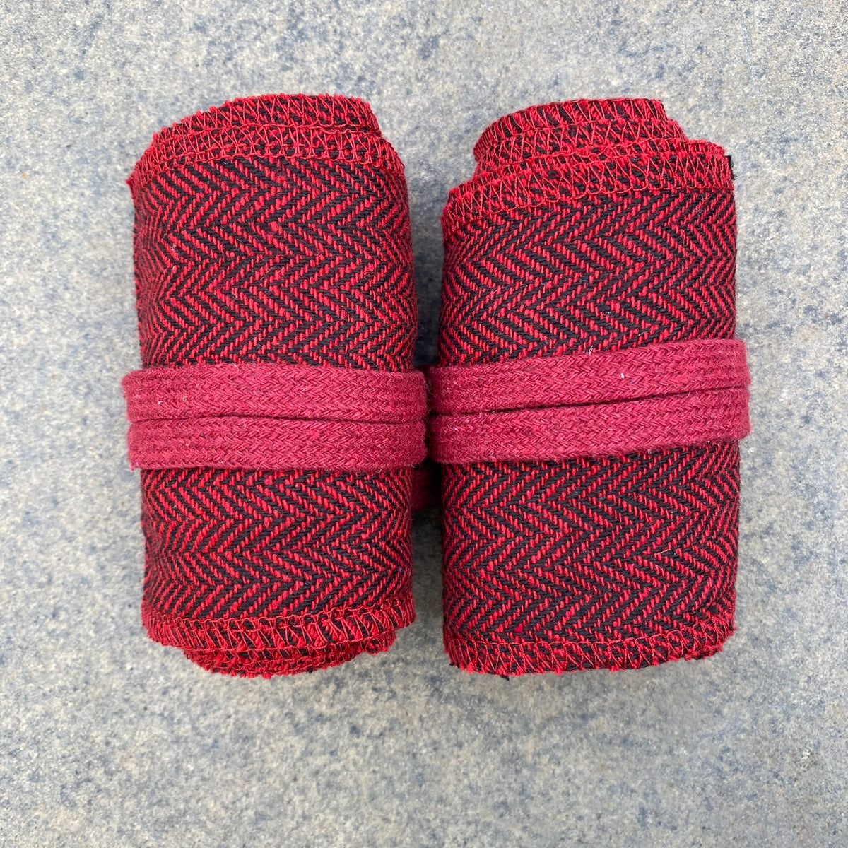 Rolled red herringbone wraps for LARP, detailed top-down view on stone surface.