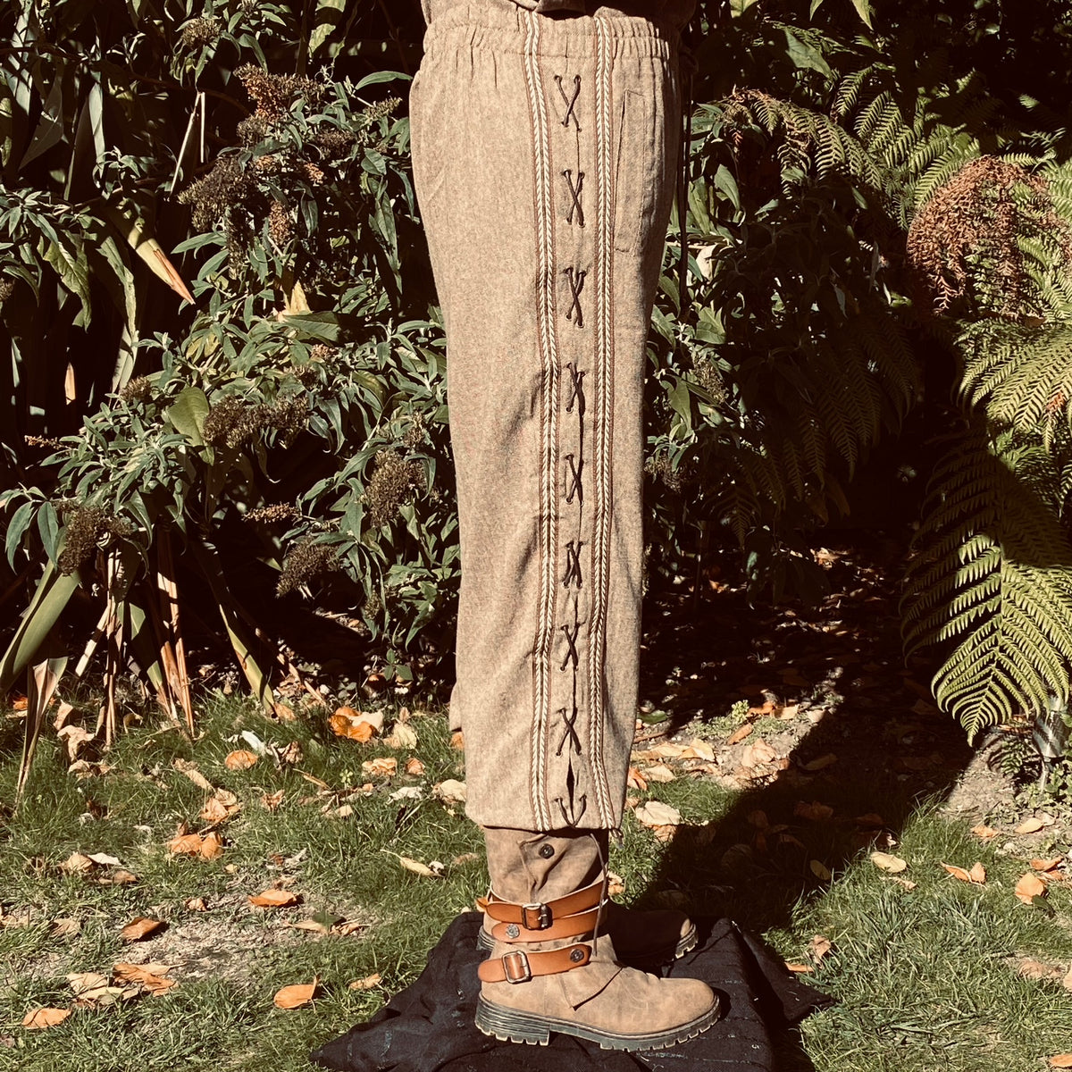 Side view of medieval LARP pants with cross-stitch detail and buckle boots.