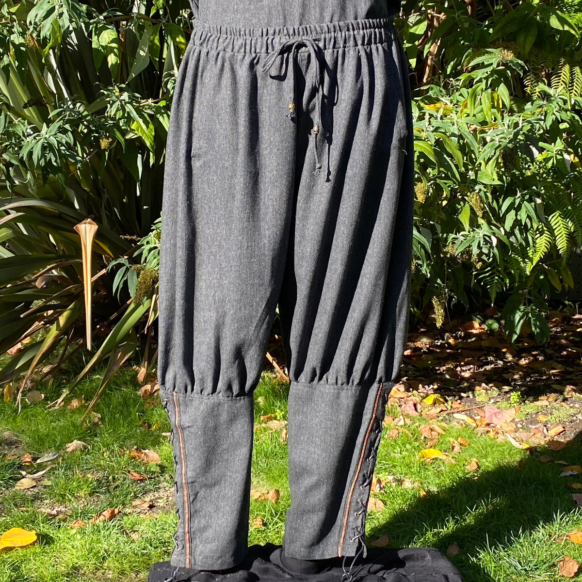 Front view of grey wool Viking pants with braided trim and crossover lacing at the calves.