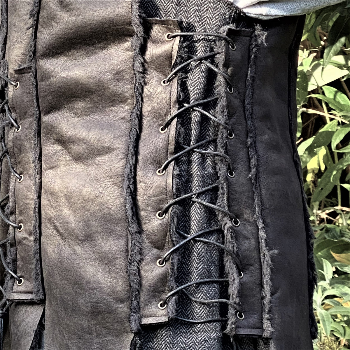 Dark medieval LARP waistcoat, close-up of textured black leather with lacing.