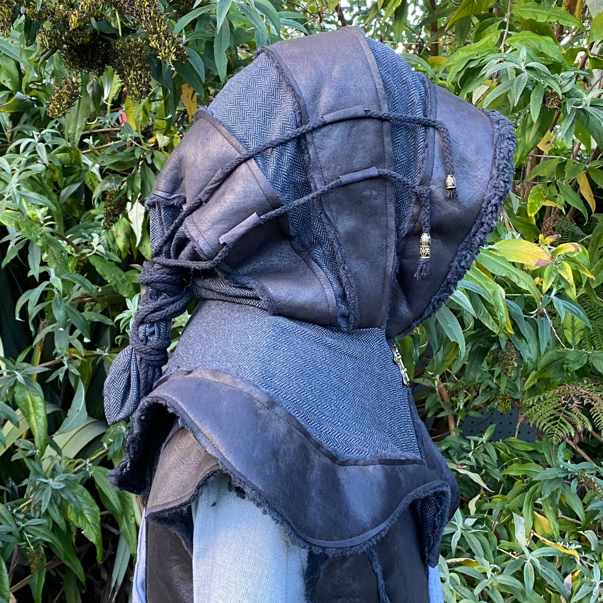 Dark LARP hood with textured fabric and beads, side view against greenery.