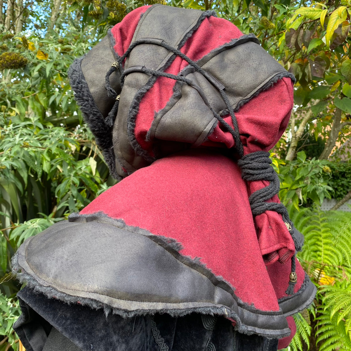 Red and black LARP hood, side view, layered with rope detail, medieval style.