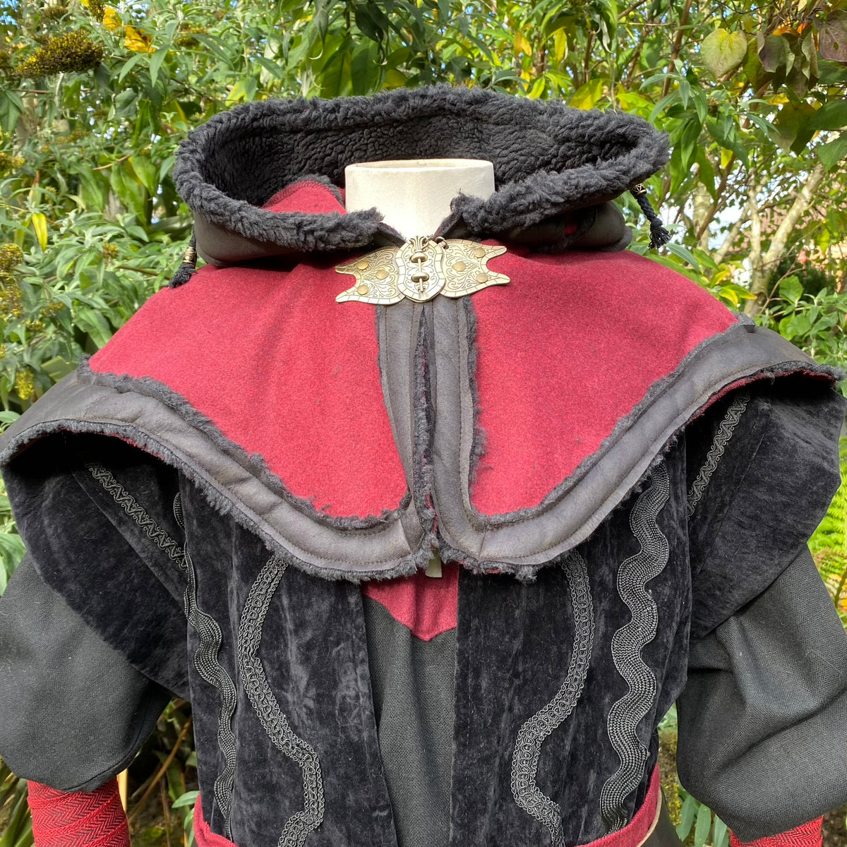 Black and red LARP hood with ornate clasp, showing fleece lining.
