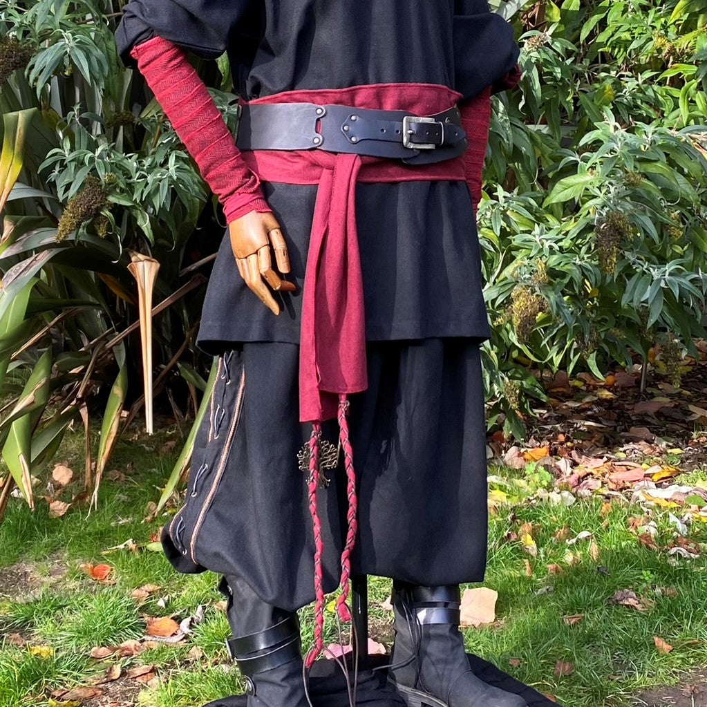 Mannequin in medieval LARP attire, red herringbone arm wraps, belt focus.
