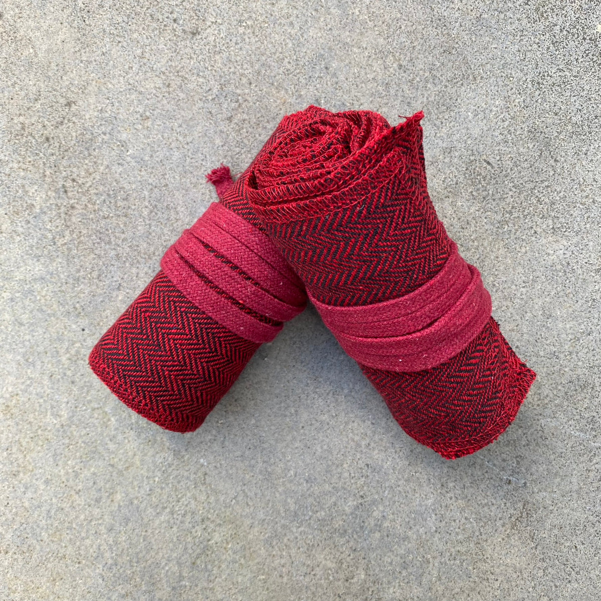 Red herringbone wool leg and arm wraps for LARP, rolled and side view.