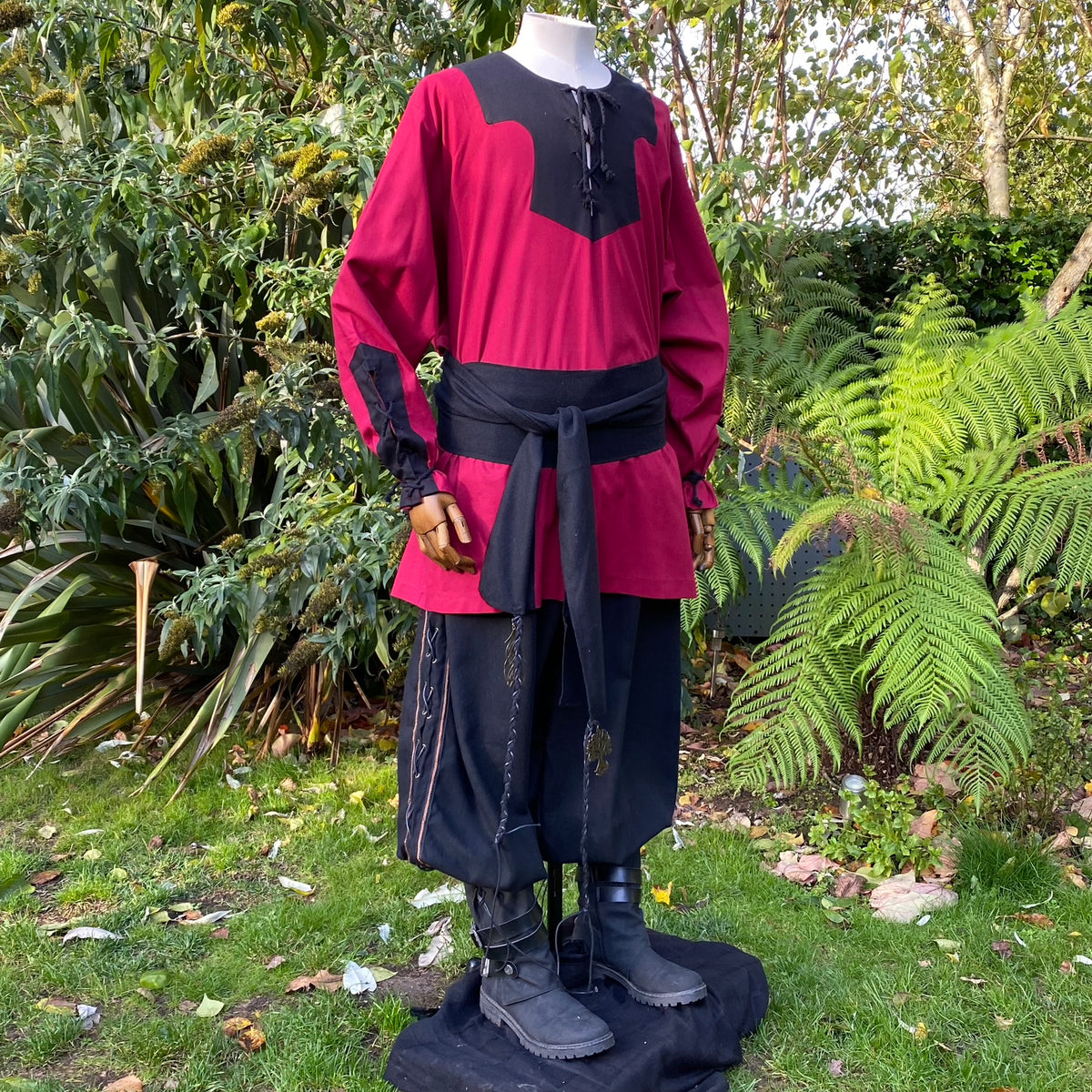 Medieval LARP outfit in garden; red tunic with black waist tie and boots visible.