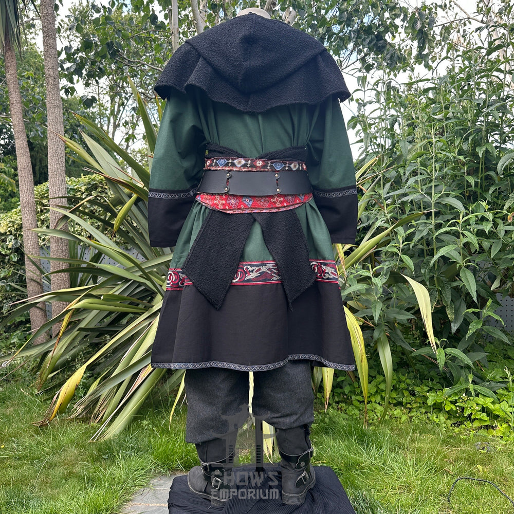 Medieval LARP outfit back view, featuring a green and black Viking tunic, hood, trousers and sash. For Renaissance Faire and historical roleplay events.