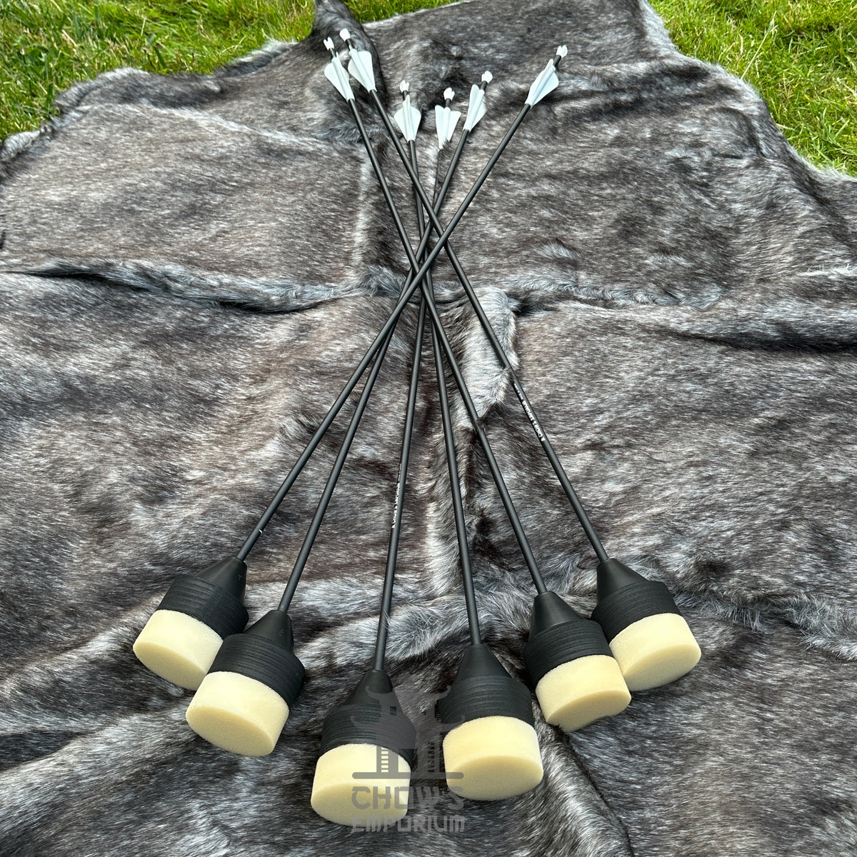 Set of arrows with black shafts and white nocks on a grey fur surface.