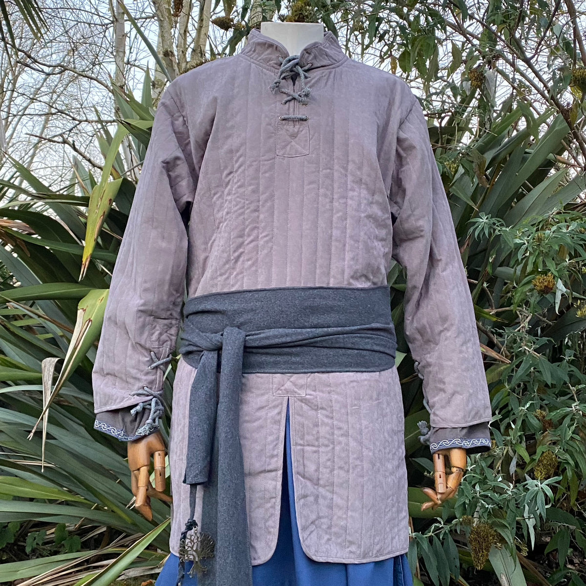 Grey medieval LARP gambeson with dark sash, displayed, front view.