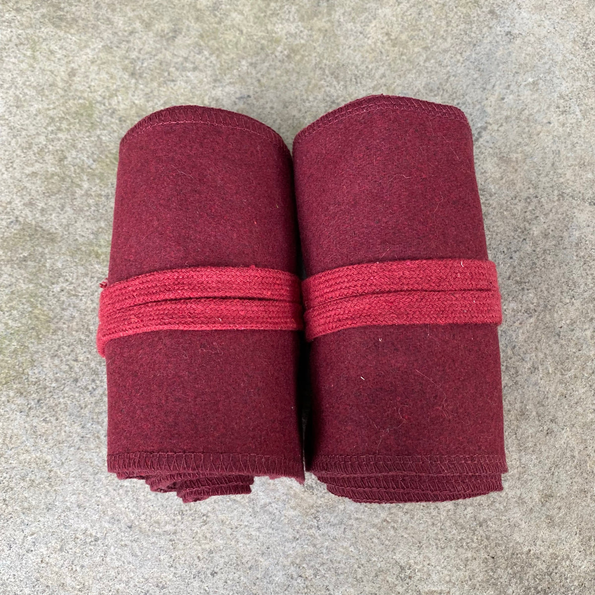 Rolled red woolen puttees for LARP, neatly tied, top view on concrete background.