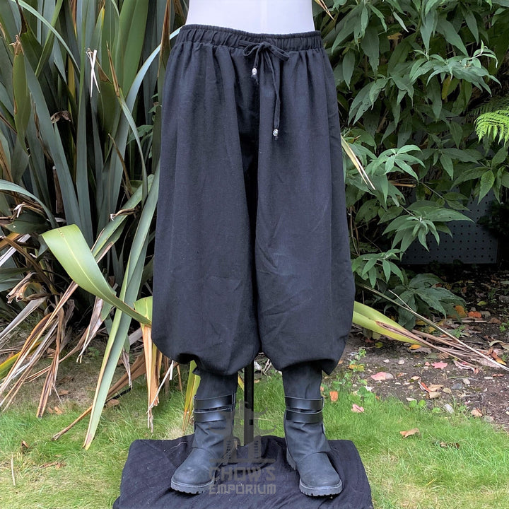 Black medieval LARP trousers, loose fit, tied waist, front view.