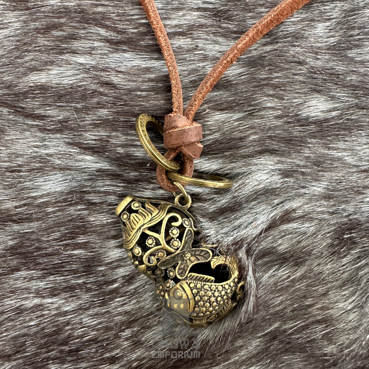Bronze fish-shaped orb necklace on brown leather cord.