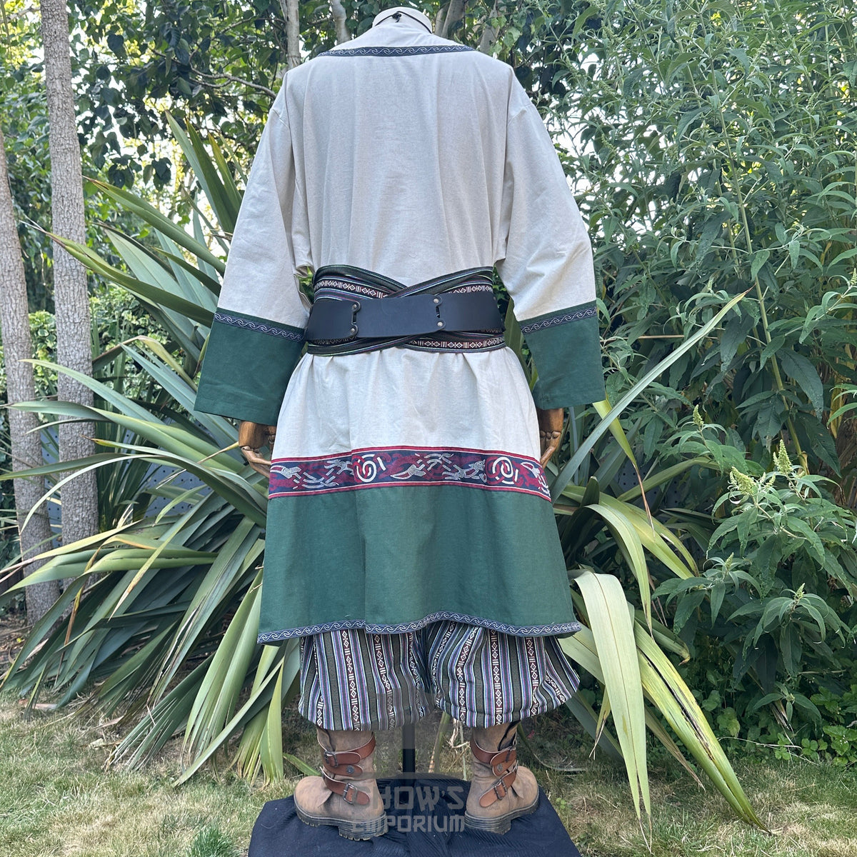 LARP medieval outfit with white tunic, green trim, sash, striped trousers, rear view.